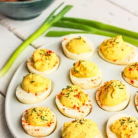 easy deviled eggs on a white tray with green onions