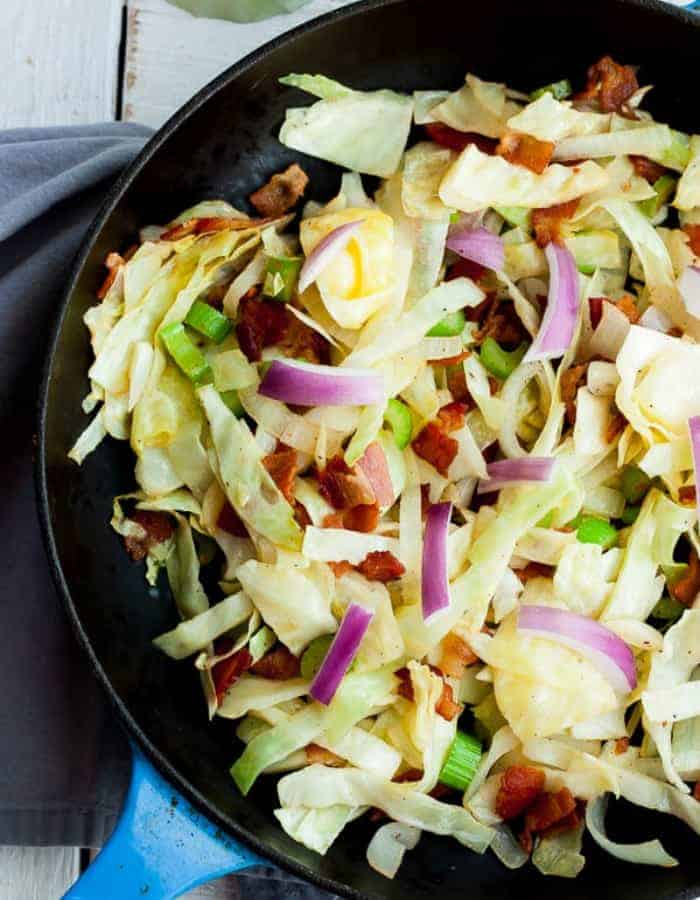 an overherad photo of fried cabbage with bacon in a skillet