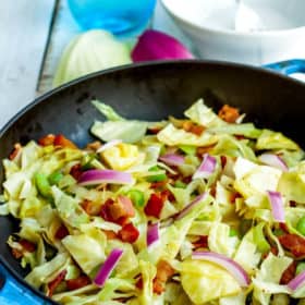 a blue skillet with fried cabbage with bacon