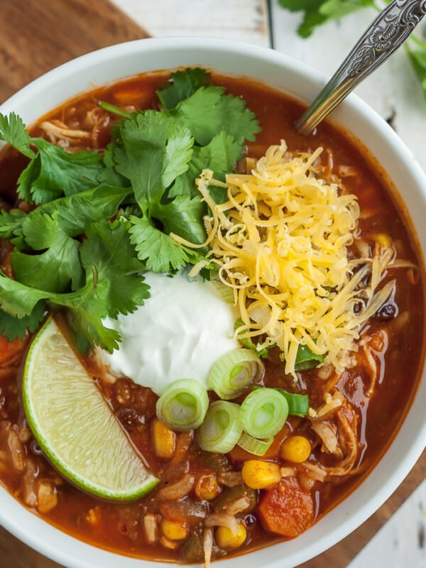 Instant Pot tortilla soup in a bowl with cilantro, sour cream, cheese, lime, and green onion