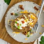 Crispy baked potatoes on a plate topped with cheese