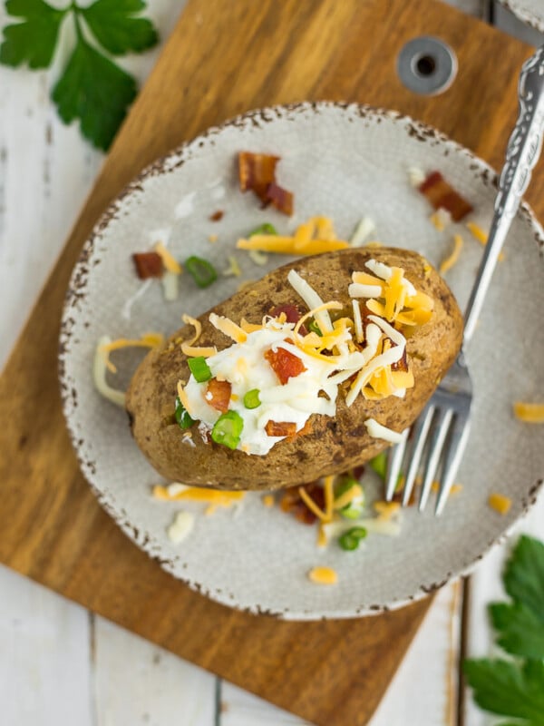 Crispy baked potatoes on a plate topped with cheese