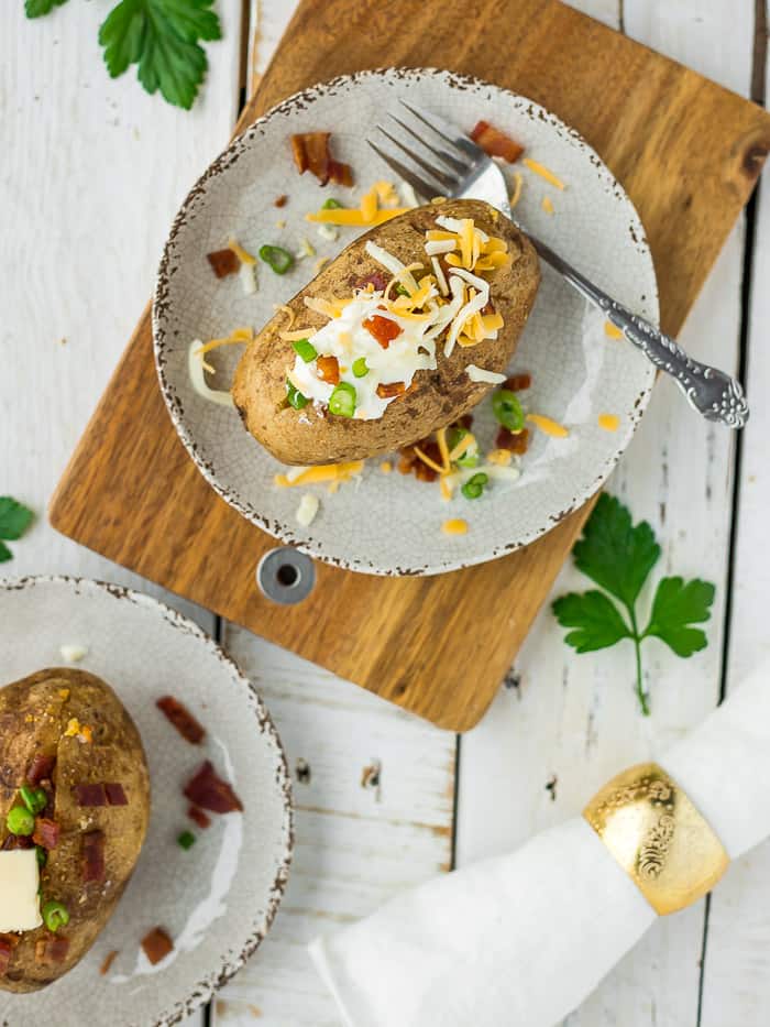 Healthy baked potatoes on a plate topped with cheese