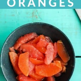 A blue bowl of segemented oranges and grapefruit with sprigs of mint