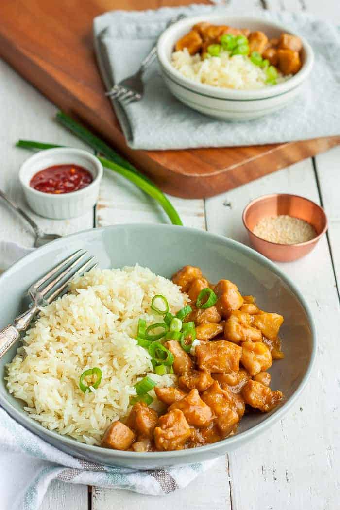 A bowl of healthy orange chicken and cauliflower rice with green onion