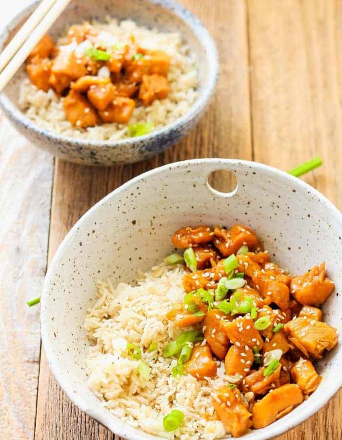 two bowls of healthy orange chicken with green onions
