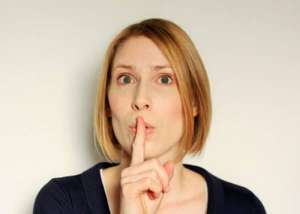 A woman with a finger up to her mouth saying 