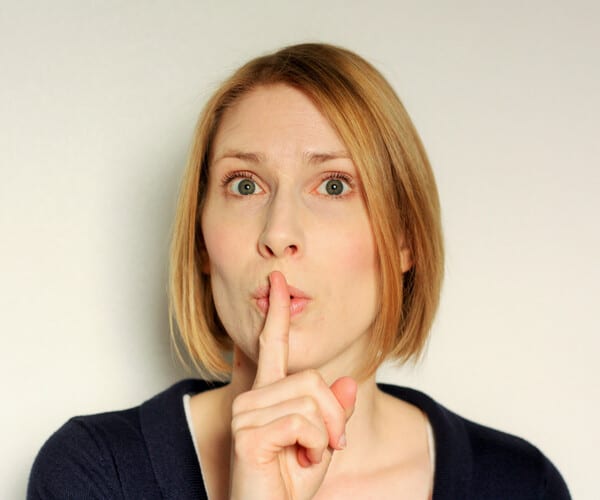 A woman with a finger up to her mouth saying "shhhhh"