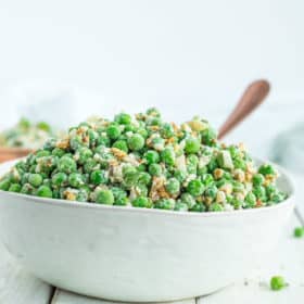a white bowl with healthy green pea salad and a bronze spoon