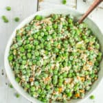 a white bowl with green pea salad and a bronze spoon
