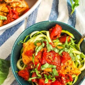 a bowl of whole30 bruschetta chicken with basil and a fork