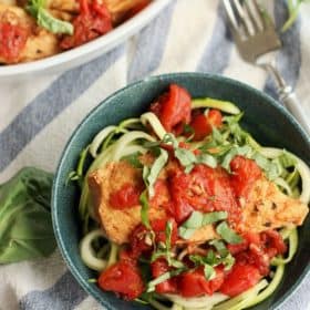 bruschetta chicken on zucchini noodles in a blue bowl topped with basil