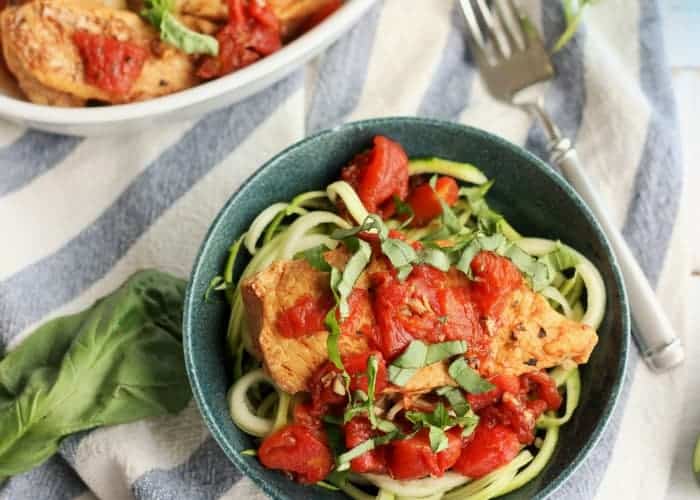 bruschetta chicken on zucchini noodles in a blue bowl topped with basil