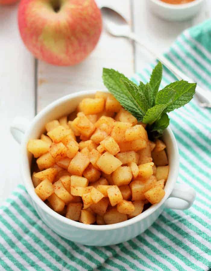 diced apples in a white bowl with mint on a striped cloth