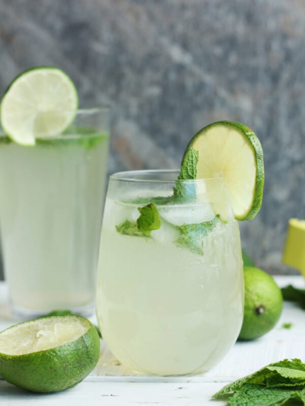 Two glasses of virgin mojitos with lime and mint on a white board