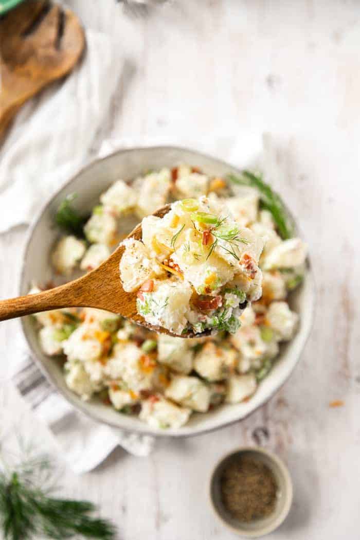 A spoon lifting a bite of potato salad