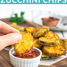 a hand dipping fried zucchini in a white bowl of marinara