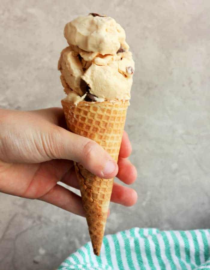 A hand holding a cone full of peanut butter ice cream