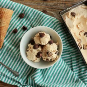 no churn peanut butter ice cream in a bowl and a pan with a sugar cone on a striped cloth