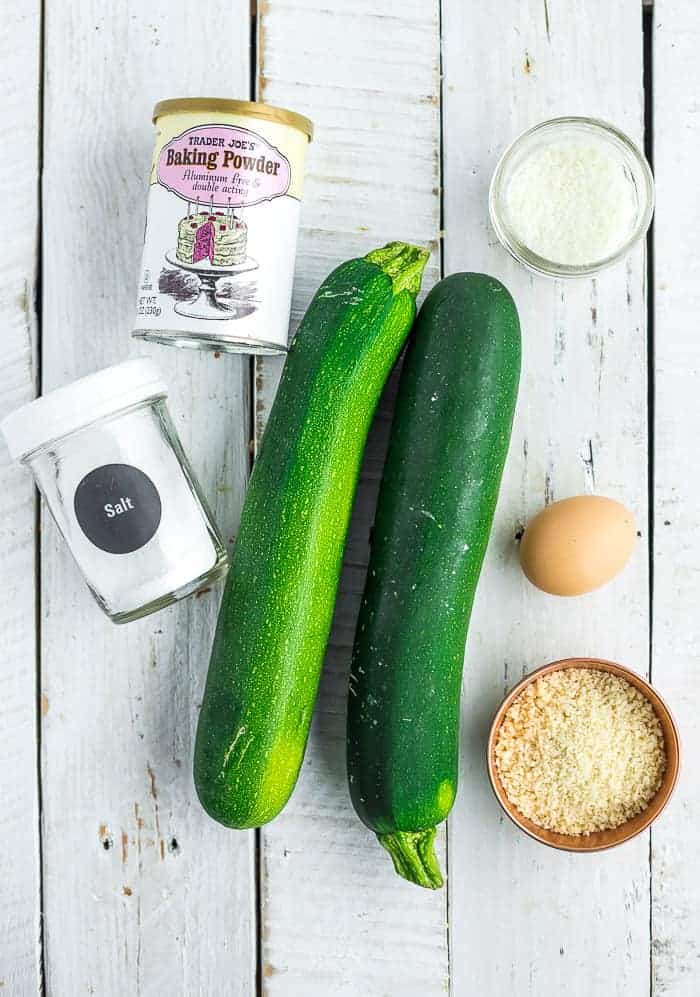 2 zucchini, an egg, and other bowls on a white board