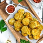 a wooden tray filled with air fryer zucchini chips on a white board