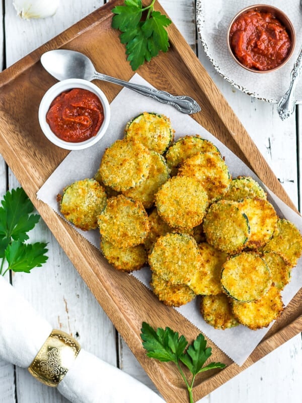 a wooden tray filled with air fryer zucchini chips on a white board