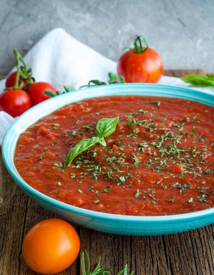 a bowl of crockpot spaghetti sauce with tomatoes and herbs.