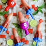 A tray of homemade watermlon popsicles on ice with mint and lime