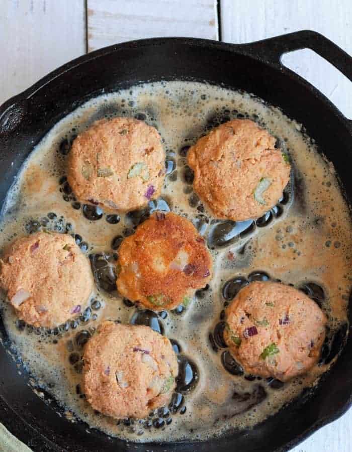 paleo salmon cakes cooking in a cast iron skillet