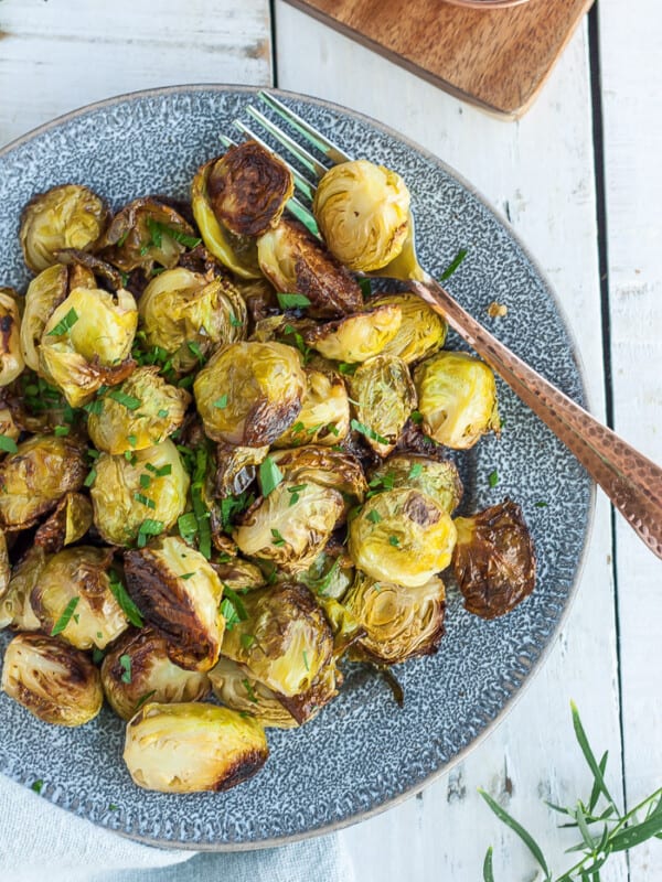 crispy brussels sprouts on a grey plate with a fork