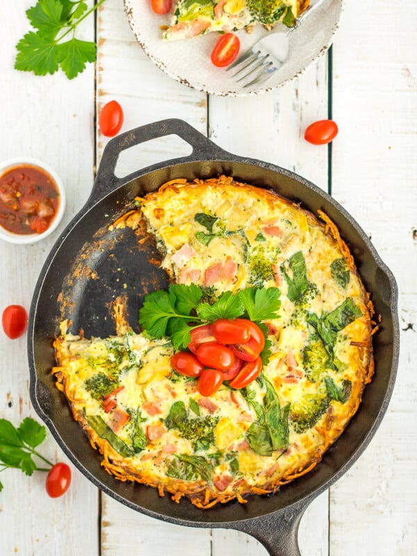 gluten-free quiche in a cast iron skillet topped with parsley and sliced tomatoes