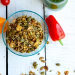 a bowl full of crunchy salad toppers with a pepper and green dressing