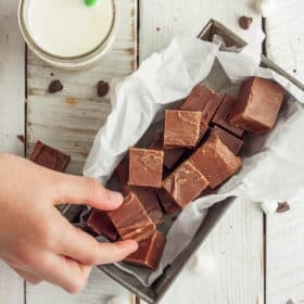 a hand reaching for a dish of chocolate fudge