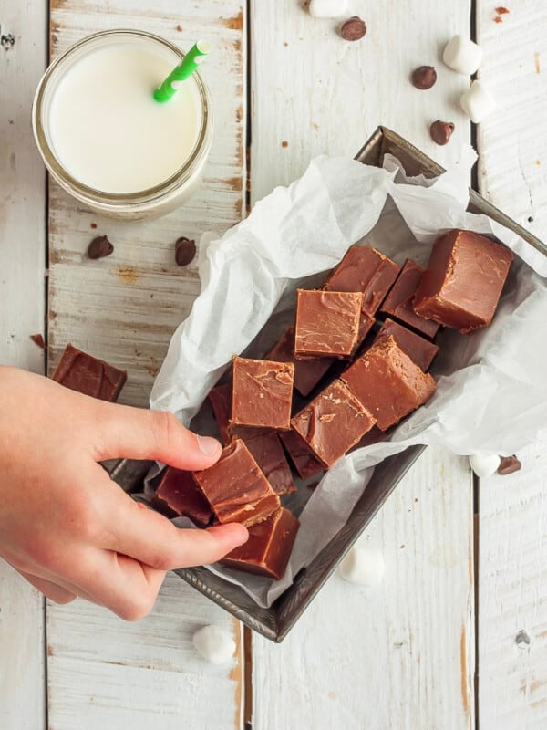 a hand reaching for a dish of chocolate fudge