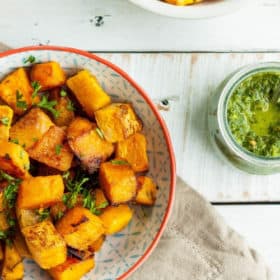 a bowl of oven-roasted butternut squash with a dish of chimichurri
