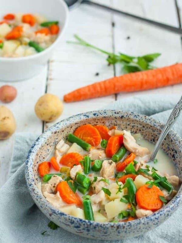a bowl of paleo chicken pot pie soup with carrots and potatoes in the background