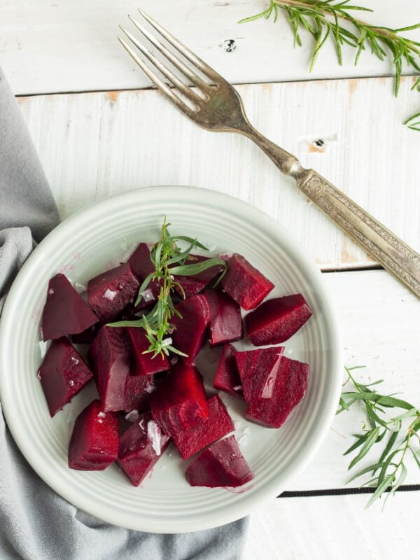 sliced pressure cooker beets on a plate with a fork and herbs