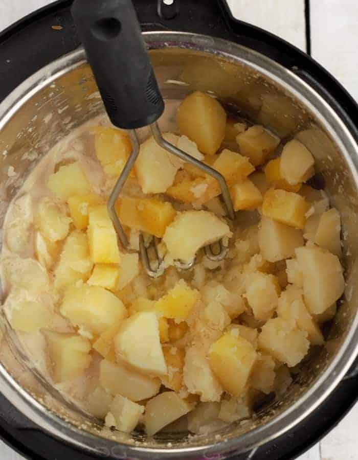 a potato masher and potatoes in an instant pot for whole30 mashed potatoes.