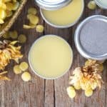 containers of homemade lip balm with beeswax on a wooden board