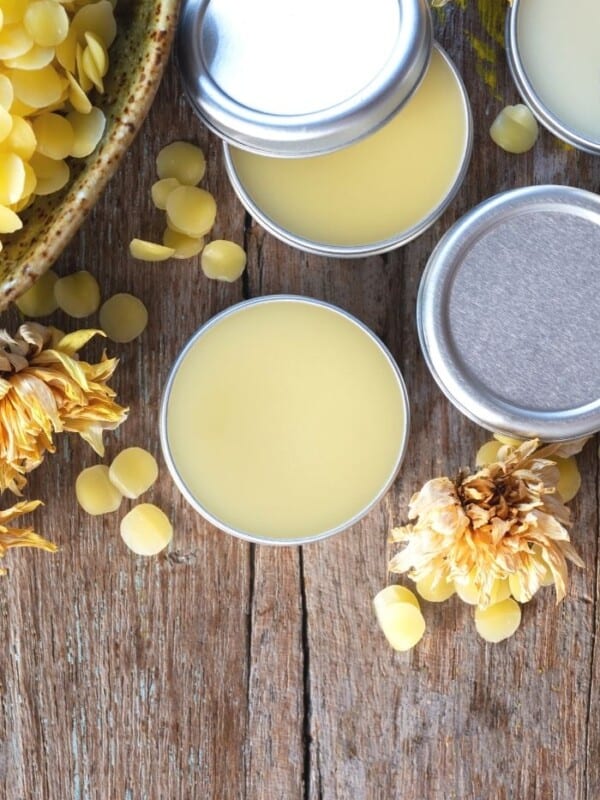 containers of homemade lip balm with beeswax on a wooden board