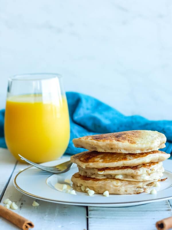 a stack of cinnamon pancakes with a glass of orange juice
