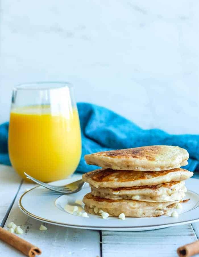 a stack of cinnamon pancakes with a glass of orange juice