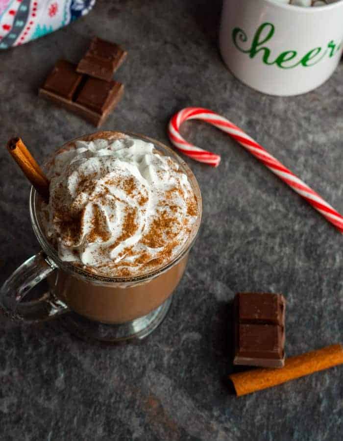 two mugs of slow cooker hot chocolate with a candy cane and cinnamon stick