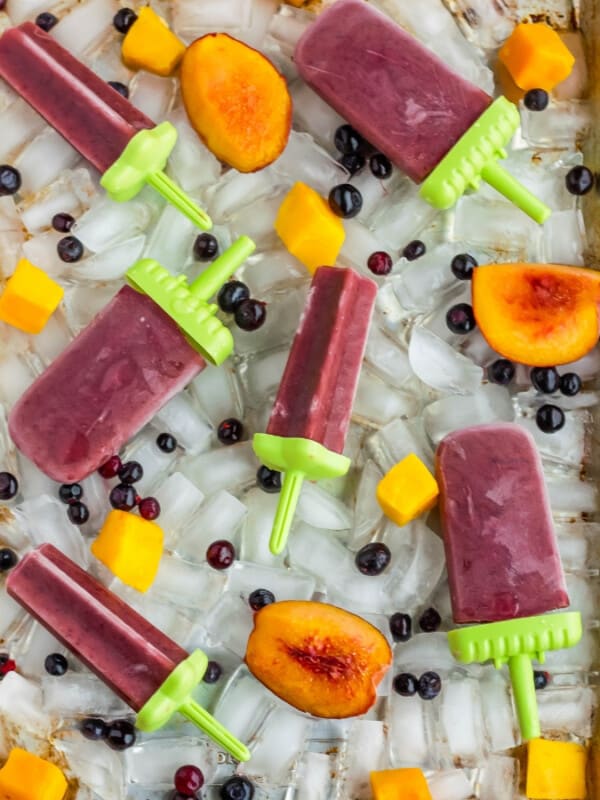 red healthy tea popsicles for sore throats and fruit on a tray of ice cubes