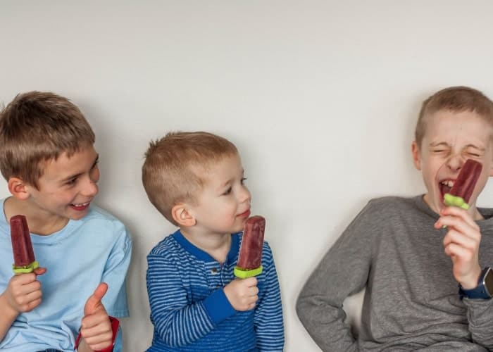 Three kids holding healthy tea popsicles for sore throats