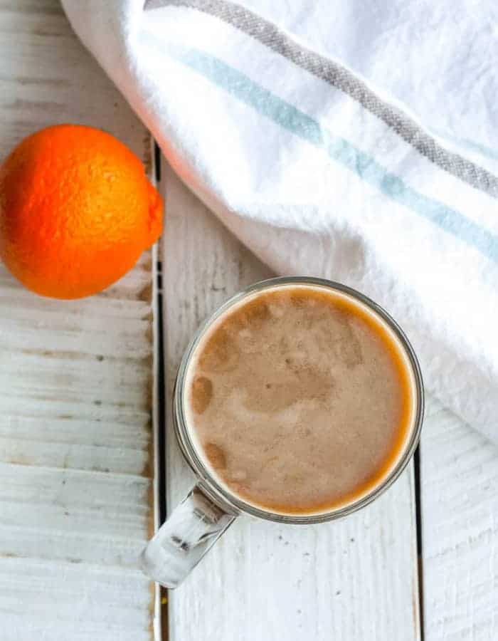 a mug of coffee with coconut coffee creamer and an orange on a white board