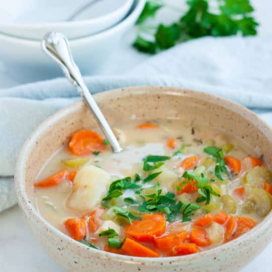 a bowl of dairy-free chicken and gnocchi soup with parsley on top
