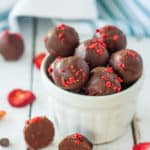 a bowl of dark chocolate truffles with strawberry flakes