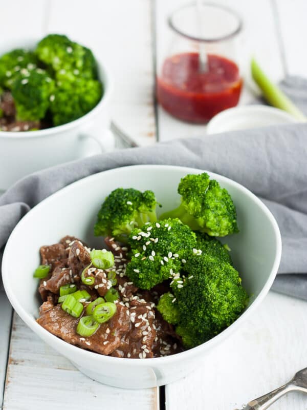 two bowls of instant pot paleo beef and broccoli with hot sauce