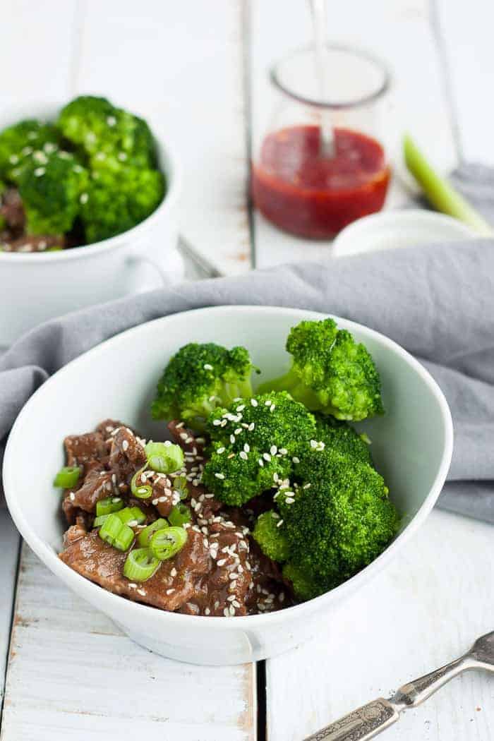 two bowls of instant pot paleo beef and broccoli with hot sauce